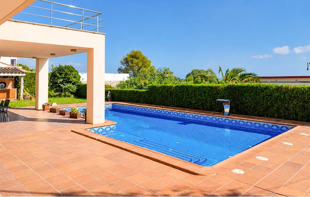 Piscina al aire libre junto a un patio embaldosado y una zona de descanso sombreada.