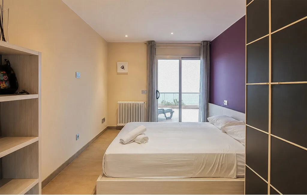 A bedroom with a bed and sliding glass doors opening onto a balcony.