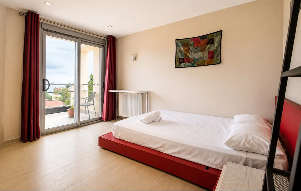 A bedroom with a low bed beside a sliding glass door.