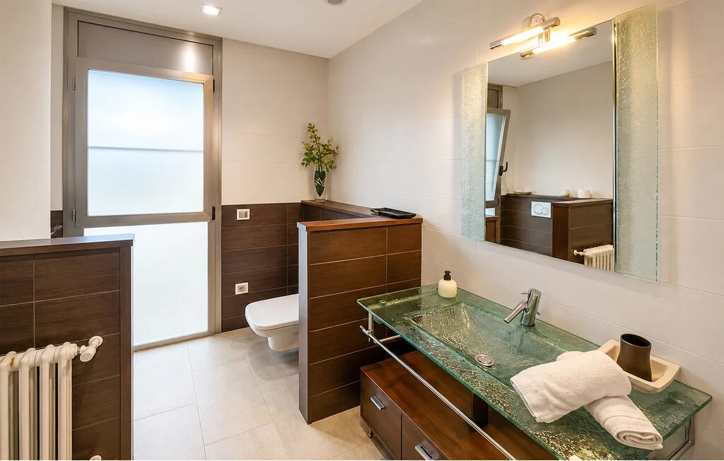 A bathroom with a glass sink and a large wall mirror.