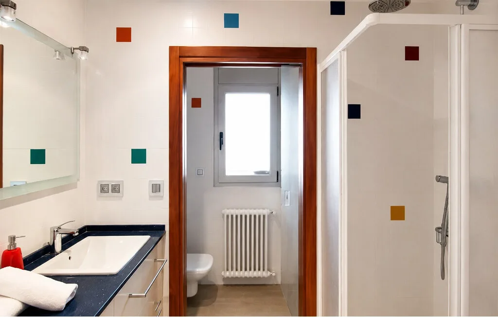 A bathroom with a sink, mirror, and shower.