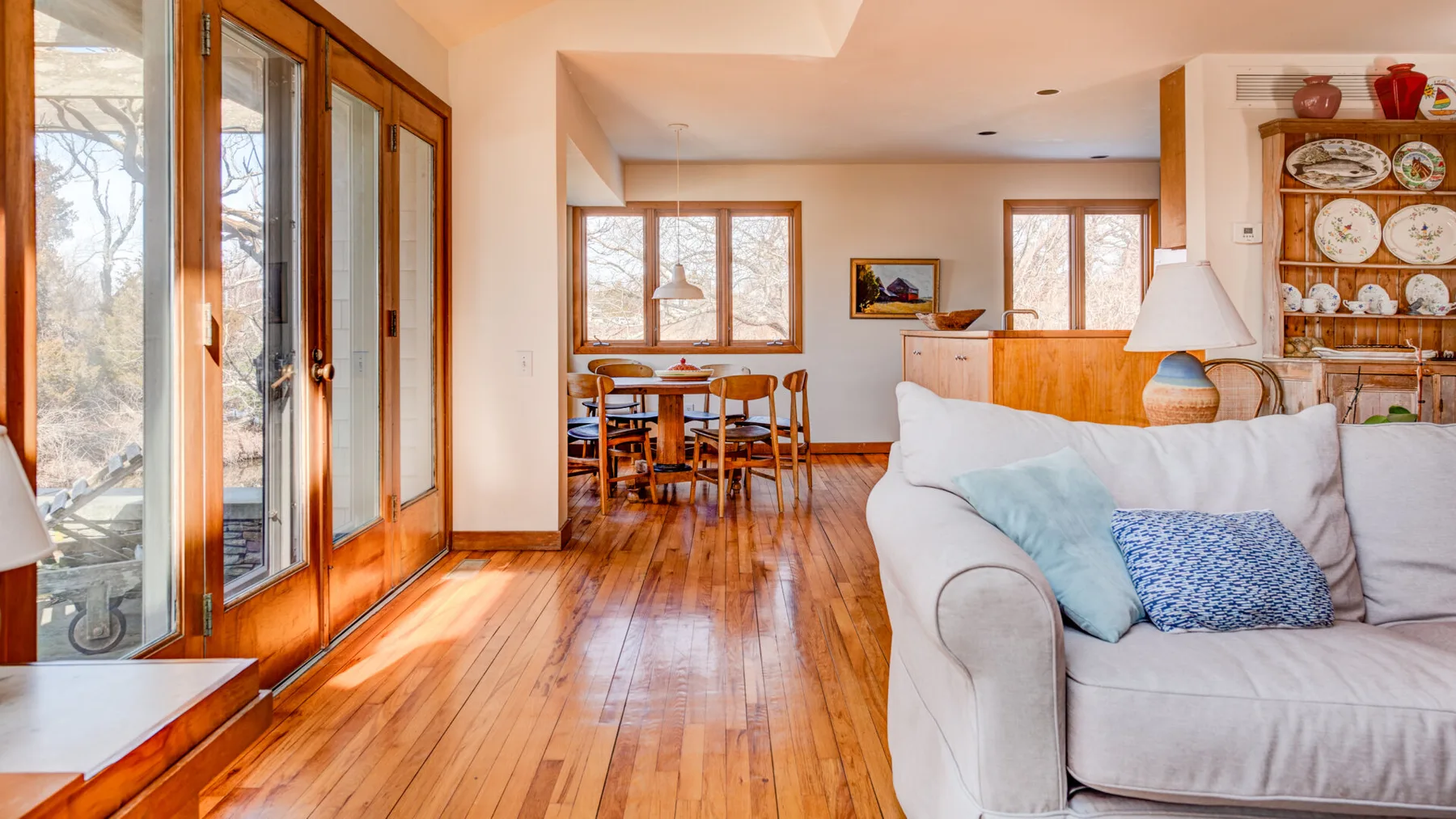 A bright living and dining area with wood floors and large windows.
