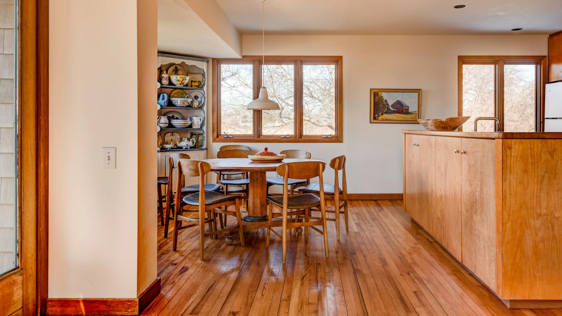 A dining area with a wooden table and chairs beside a kitchen counter.