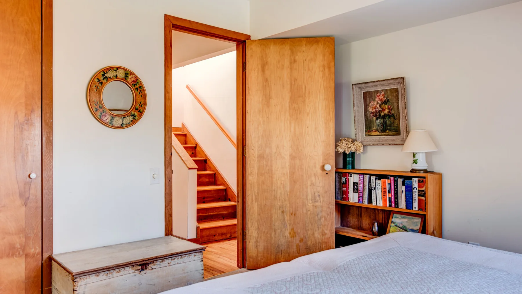 A bedroom with a bed, an open wooden door, and a bookcase.