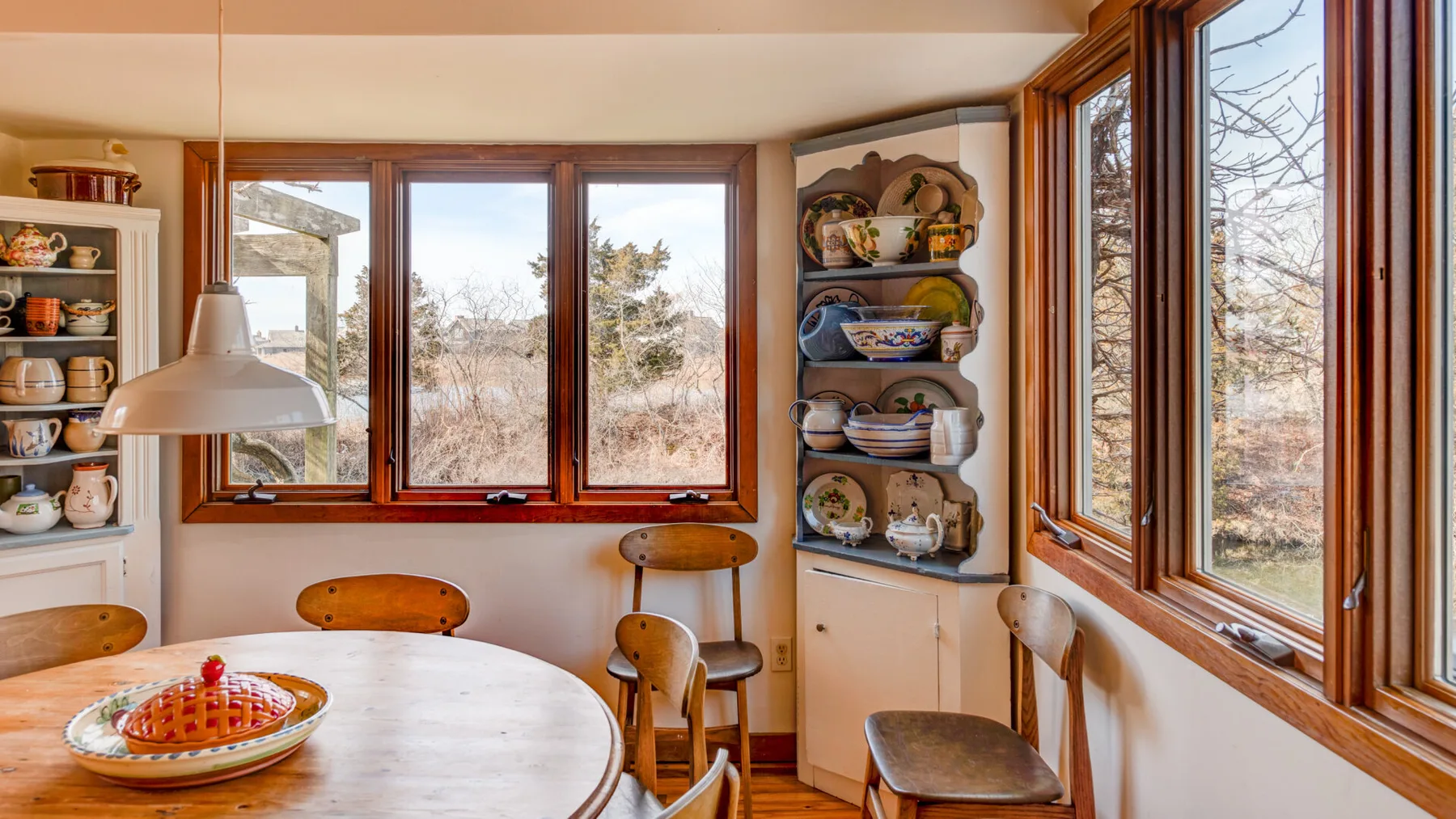 A dining nook with a round table and large windows overlooking trees.