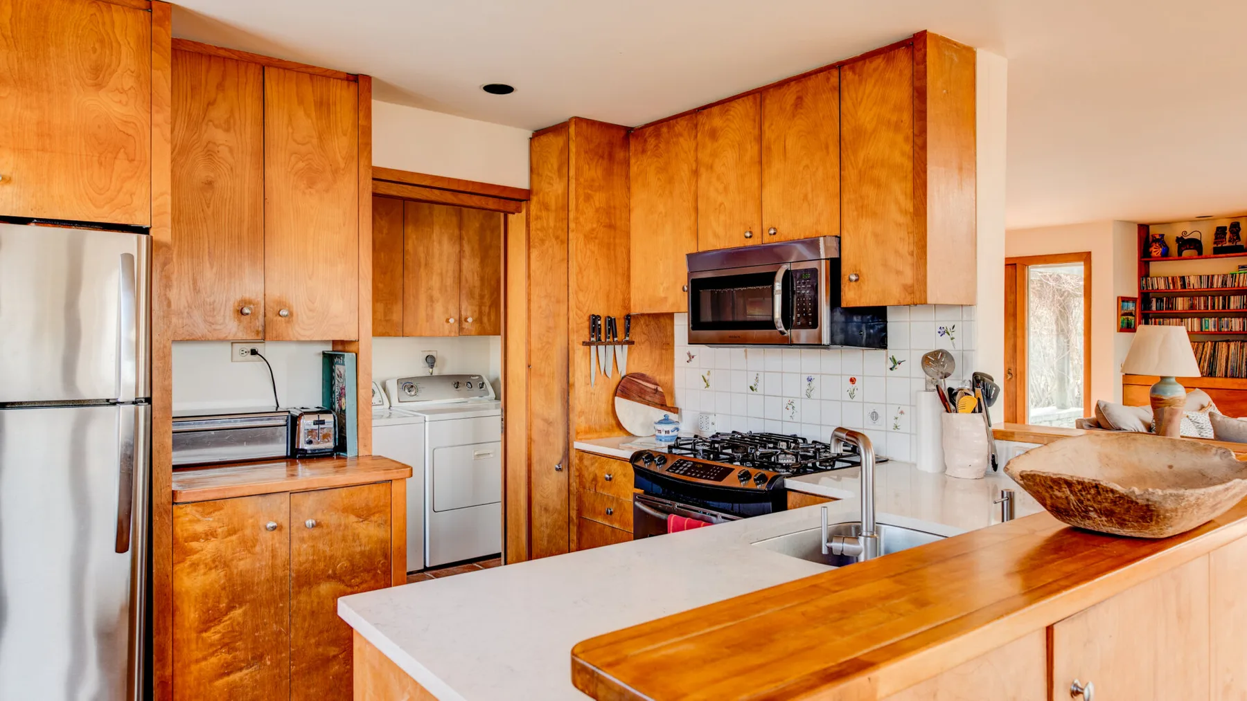 A kitchen with wooden cabinetry, a cooking range, and a counter with a sink.