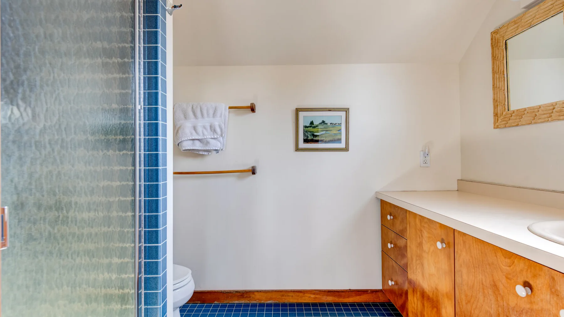 A bathroom with a tiled shower, sink, and wooden vanity.