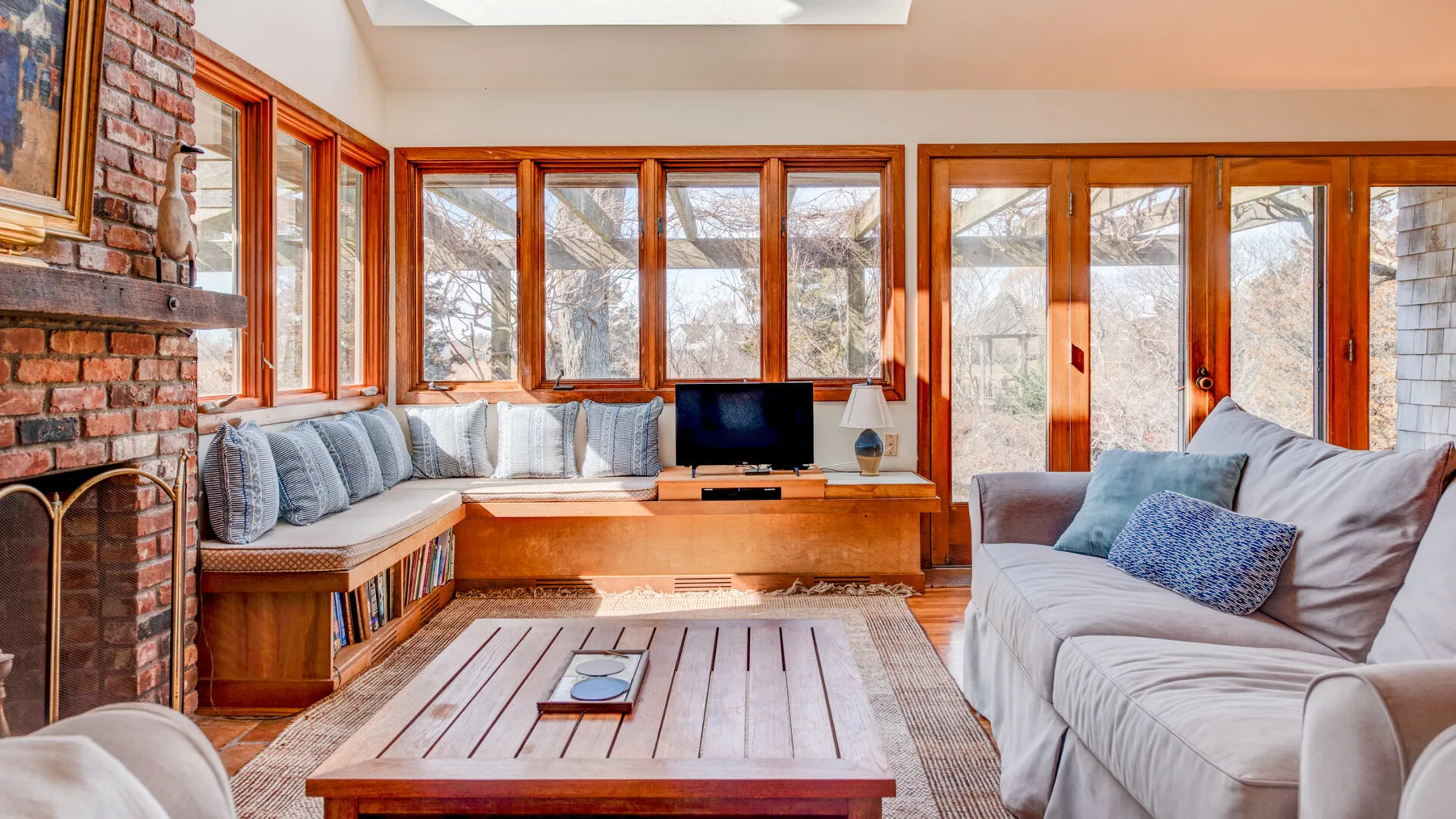 Una sala luminosa con grandes ventanas y una mesa de centro de madera.