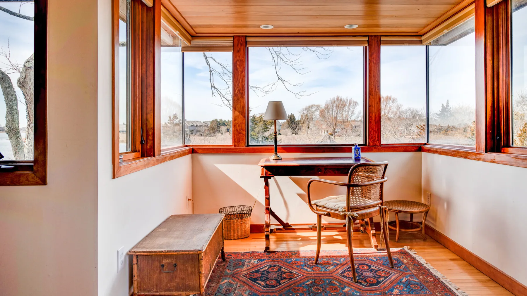A bright sunroom with large windows, a table, and a chair.