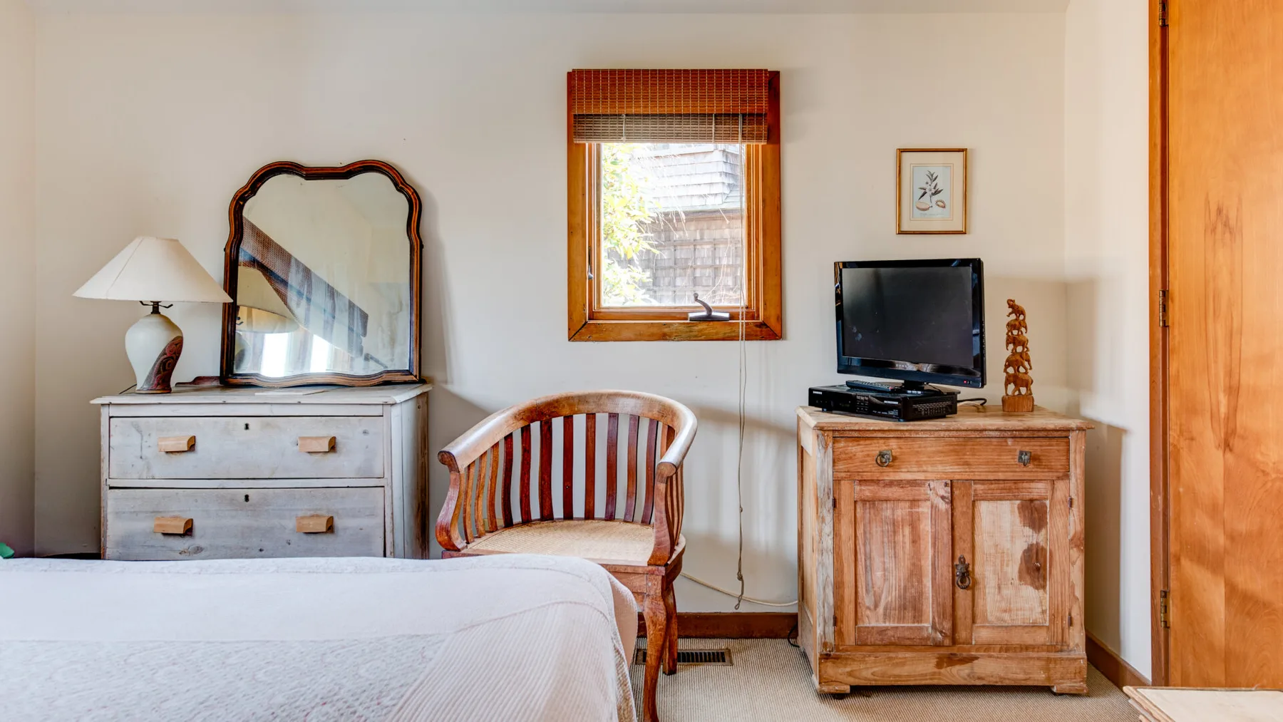 A bedroom with a bed, striped seating, and a wooden cabinet beneath a window.