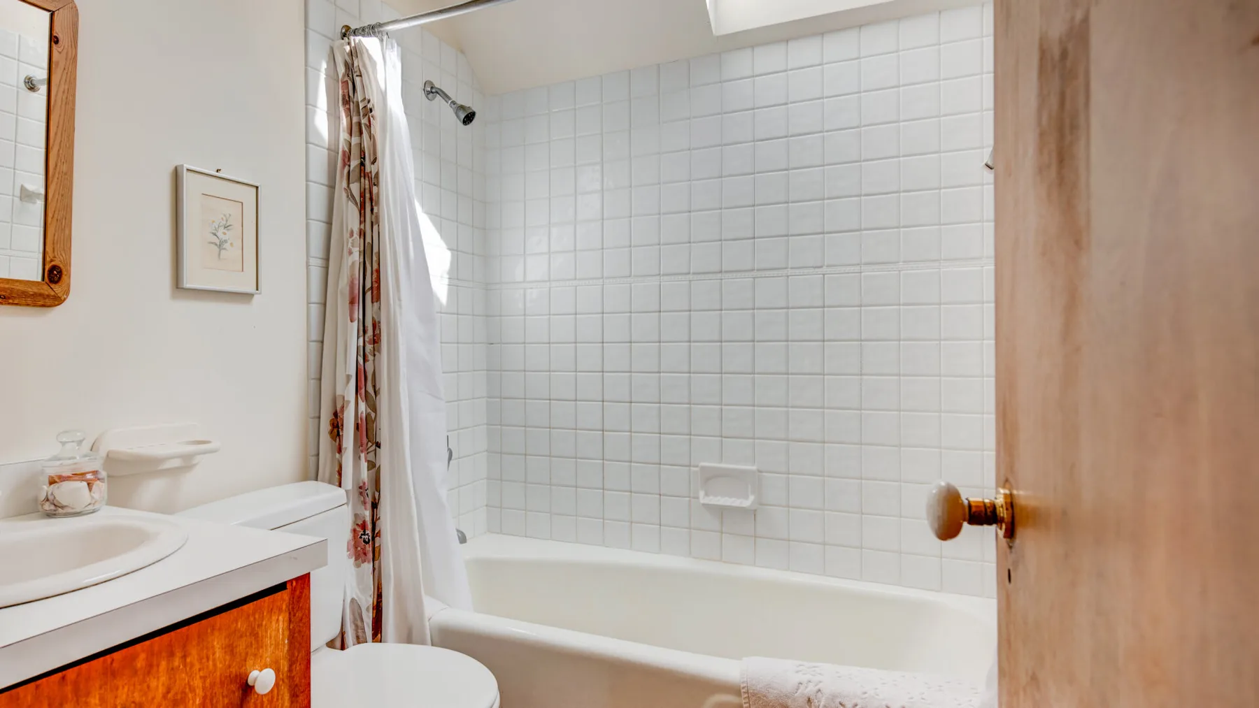 A bathroom with a bathtub, tiled walls, and a sink.