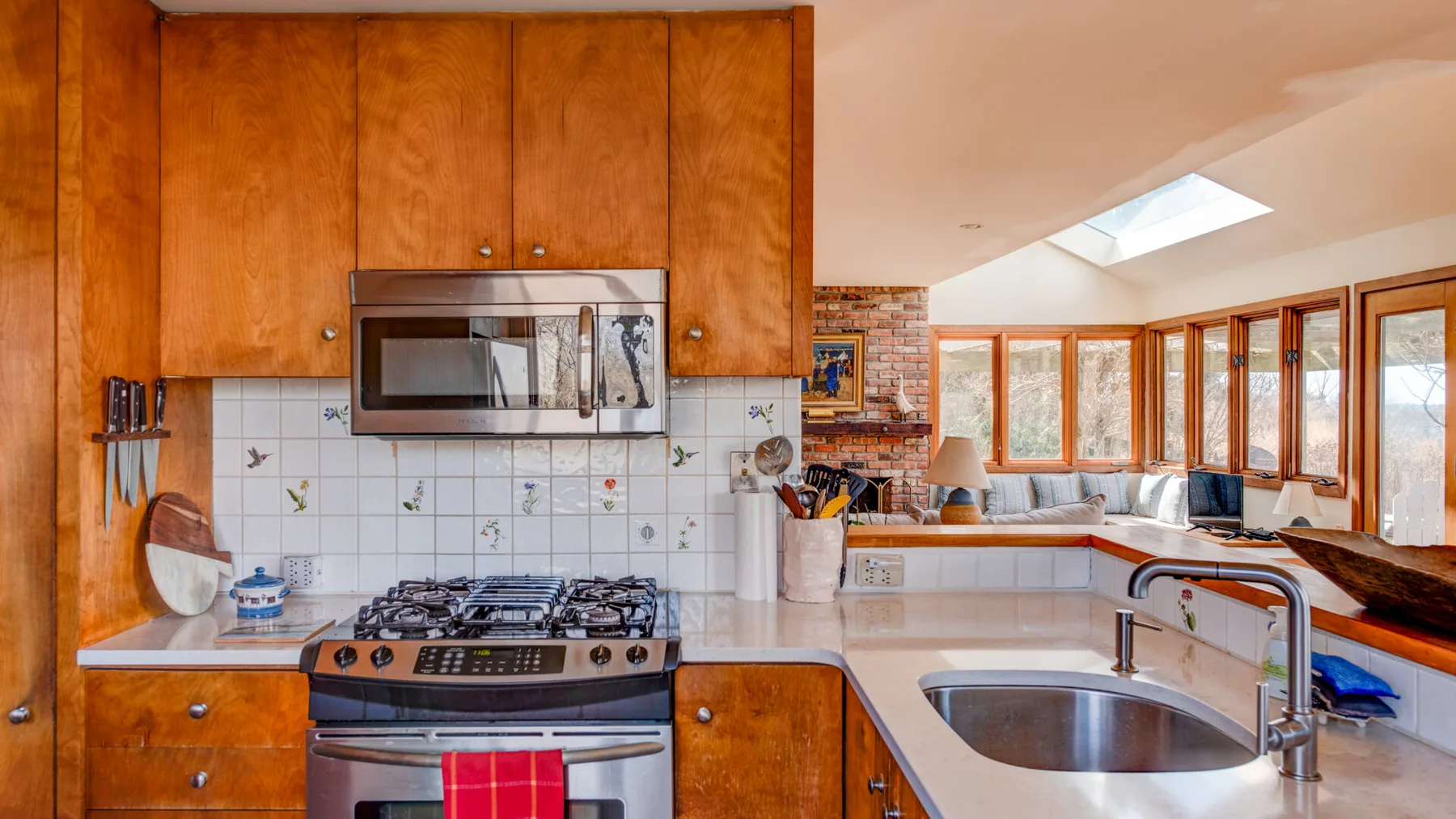 A bright kitchen with wooden cabinets, a gas range, and a curved counter.