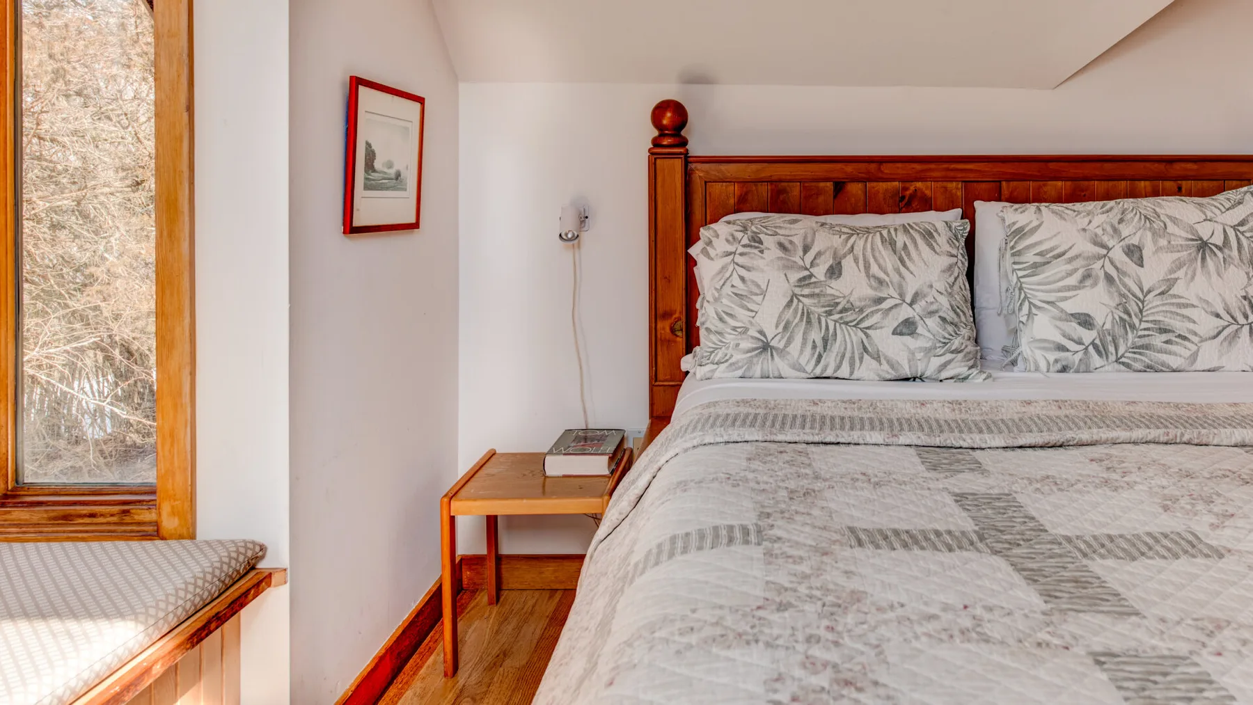 A bedroom with a wooden bed, patterned bedding, and a window.