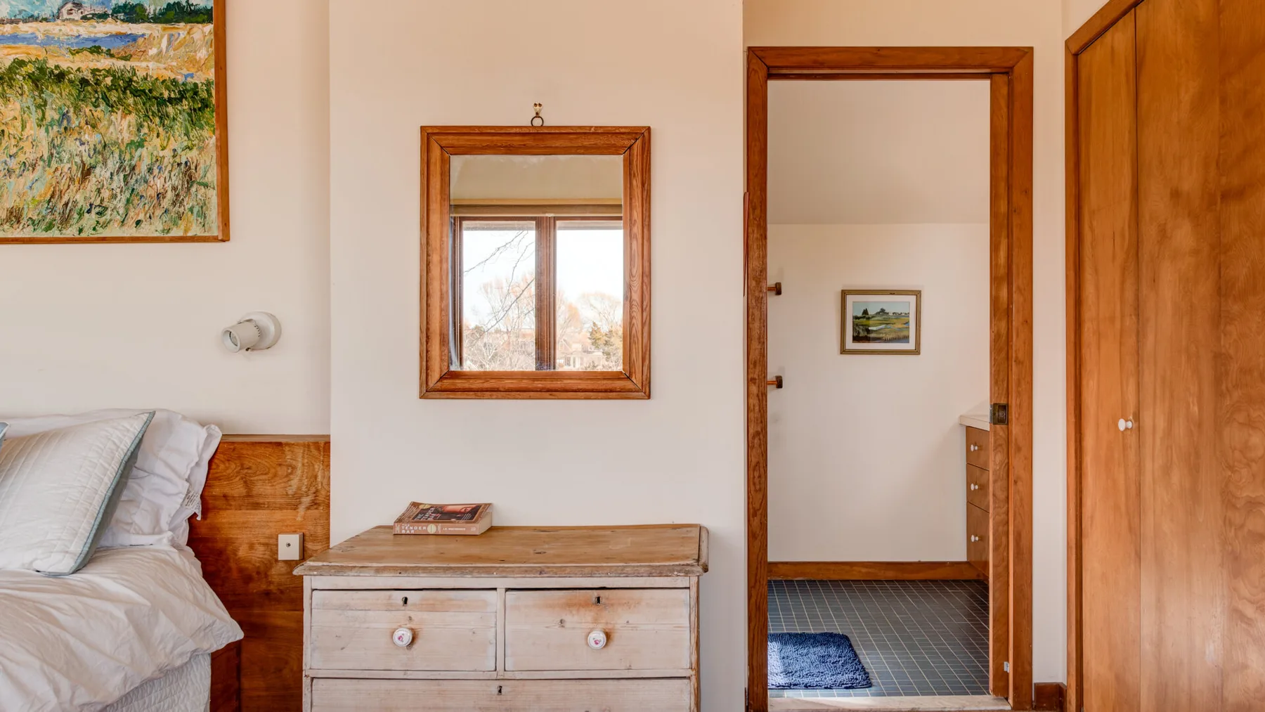 A bedroom with a bed, wooden dresser, and open doorway.