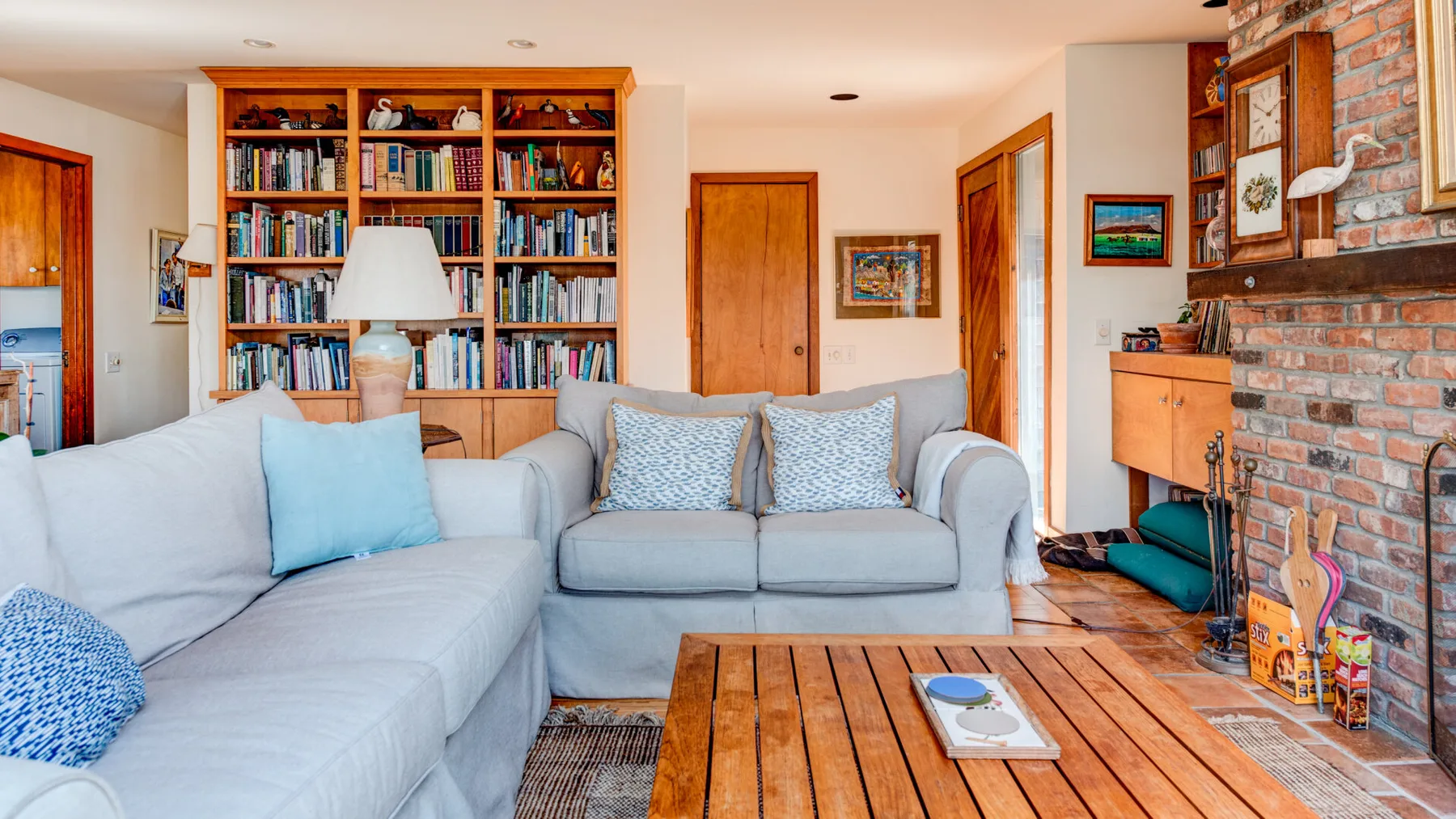 A living room with light-colored seating, a wooden coffee table, and a wall of bookshelves.
