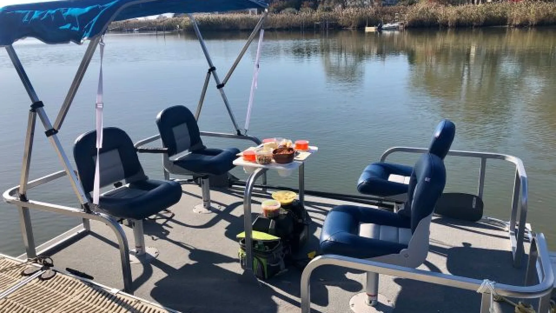 Una zona de asientos en un barco con una mesa pequeña junto al agua tranquila.
