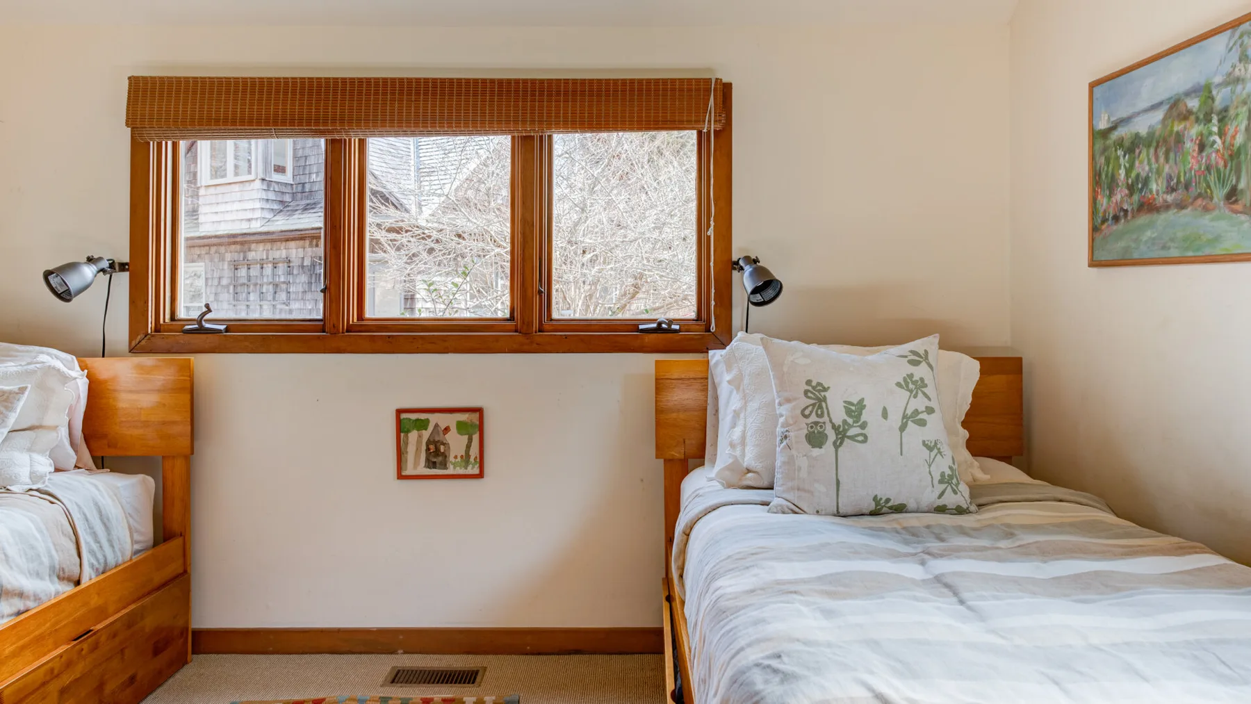 A bedroom with two beds beneath a wide window.