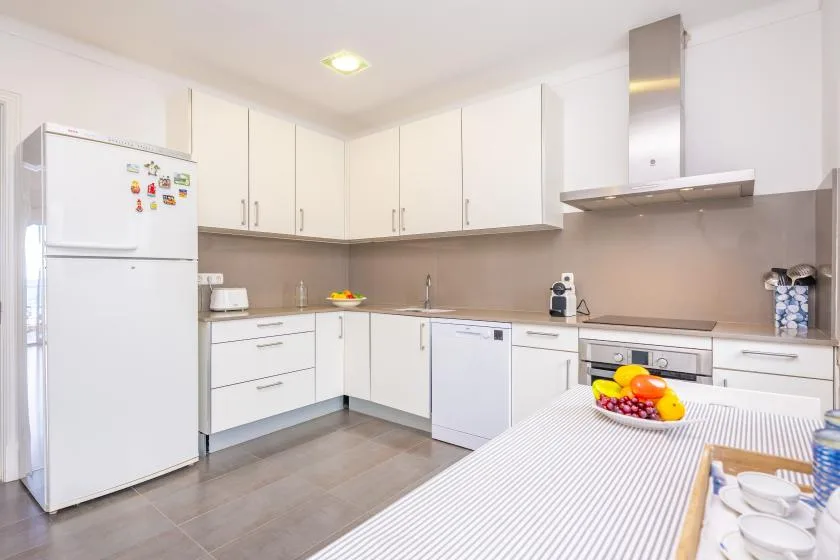 A bright kitchen with white cabinets, appliances, and a dining table.