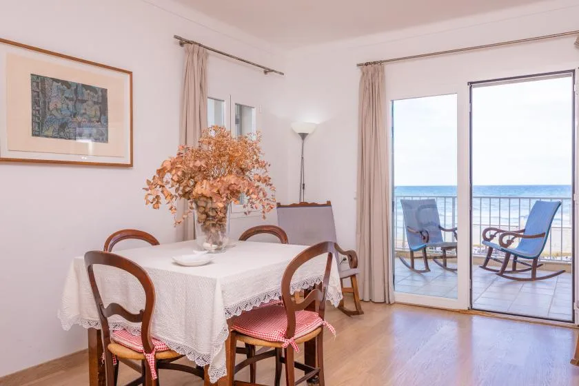 A dining area with a table and seating beside glass doors opening onto a balcony.