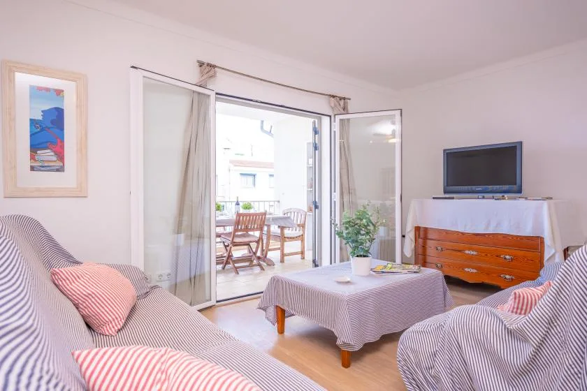 A bright living room with striped seating, a television, and an open patio door.