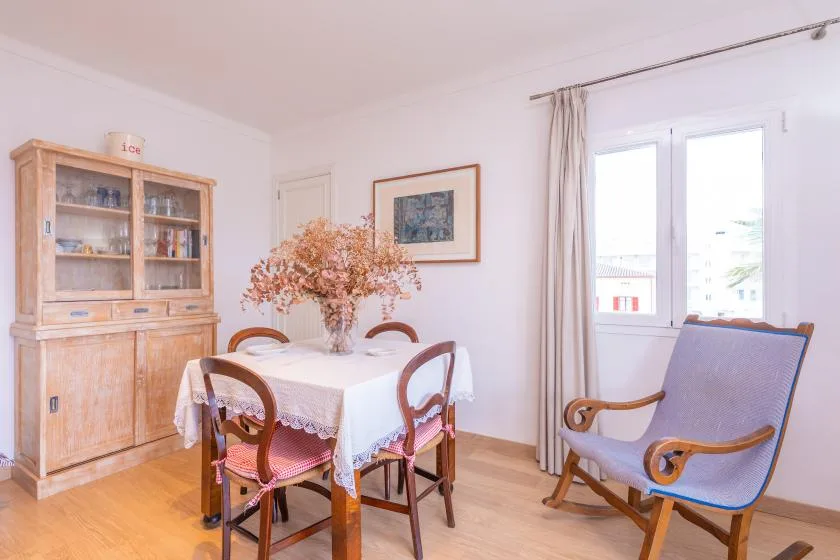 A bright dining area with a table, wooden chairs, and a large cabinet.