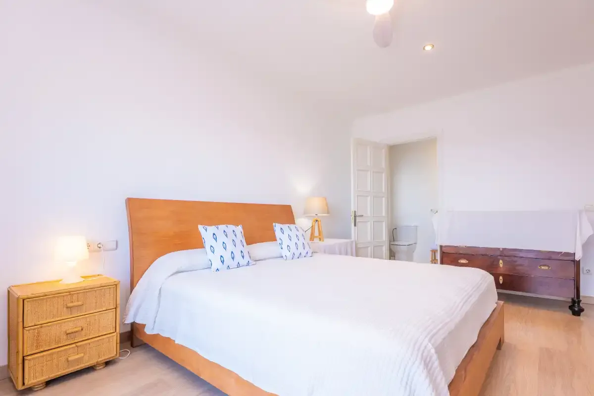 A bedroom with a large bed and wooden bedside tables.