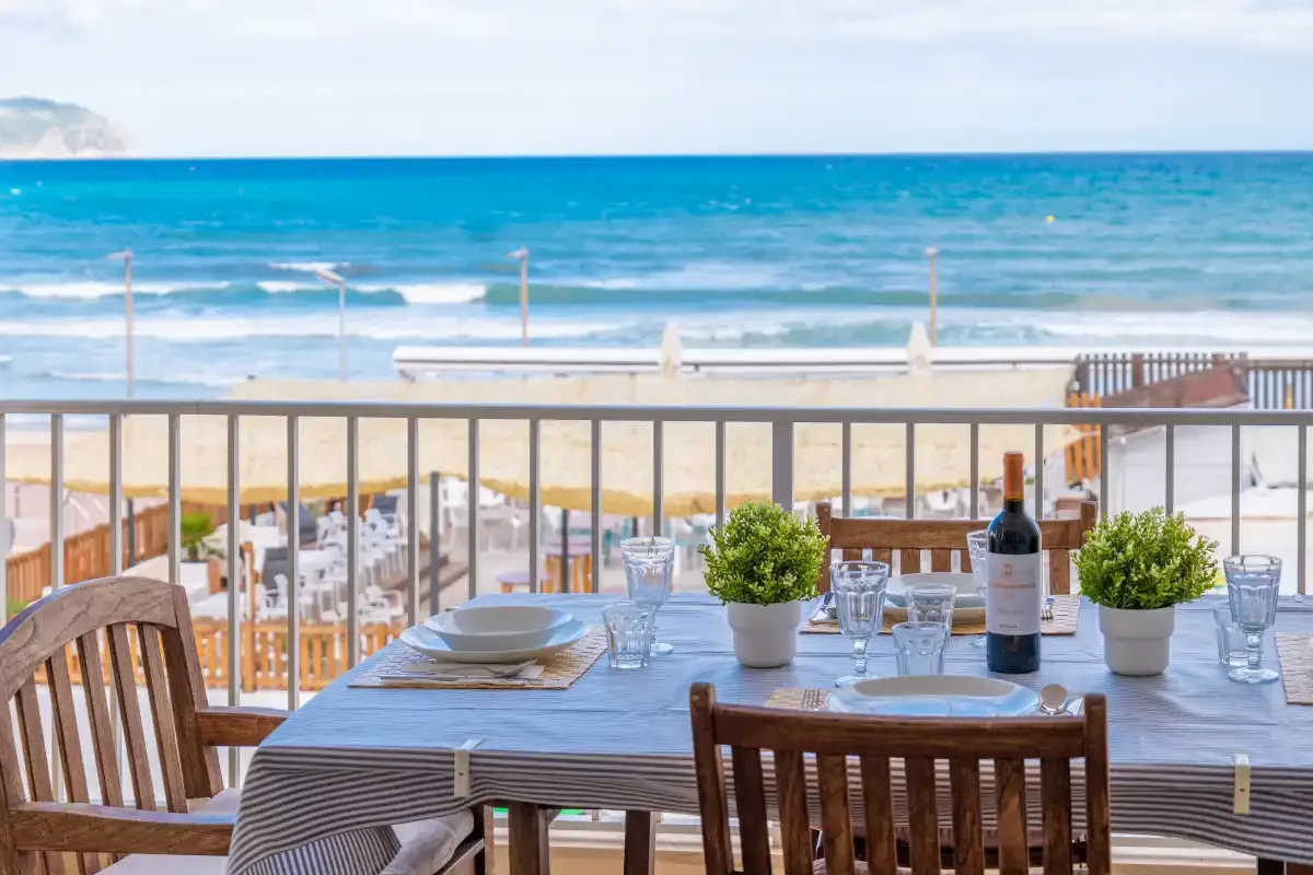 A seaside dining table overlooks the beach and ocean from a terrace.