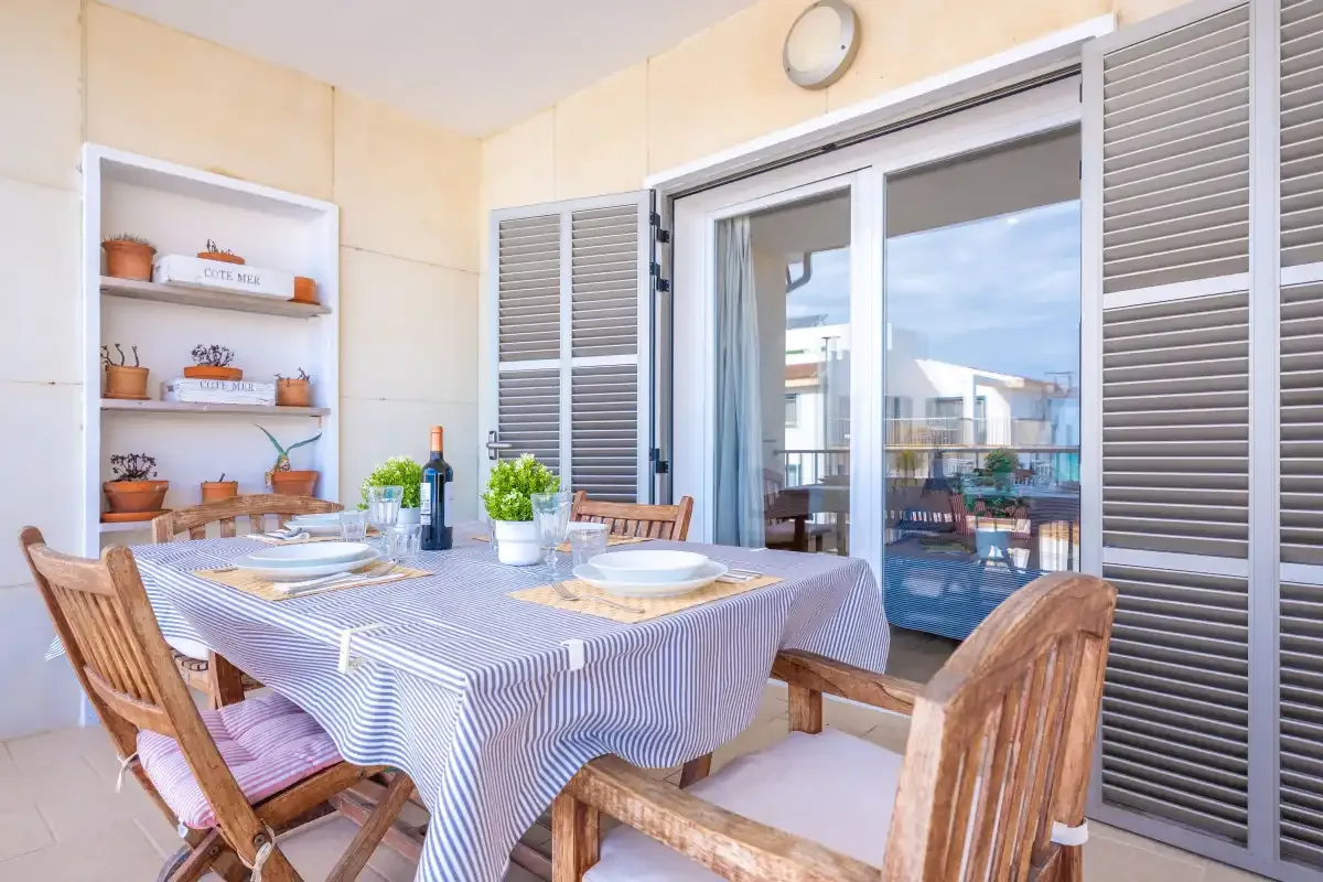 A dining area with a table set beside open glass doors and a balcony.