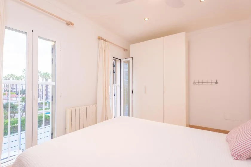 A bright bedroom with a large bed and tall windows opening onto a balcony.