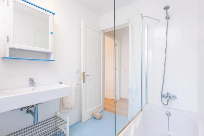 A bright bathroom with a sink, shower, and open doorway.