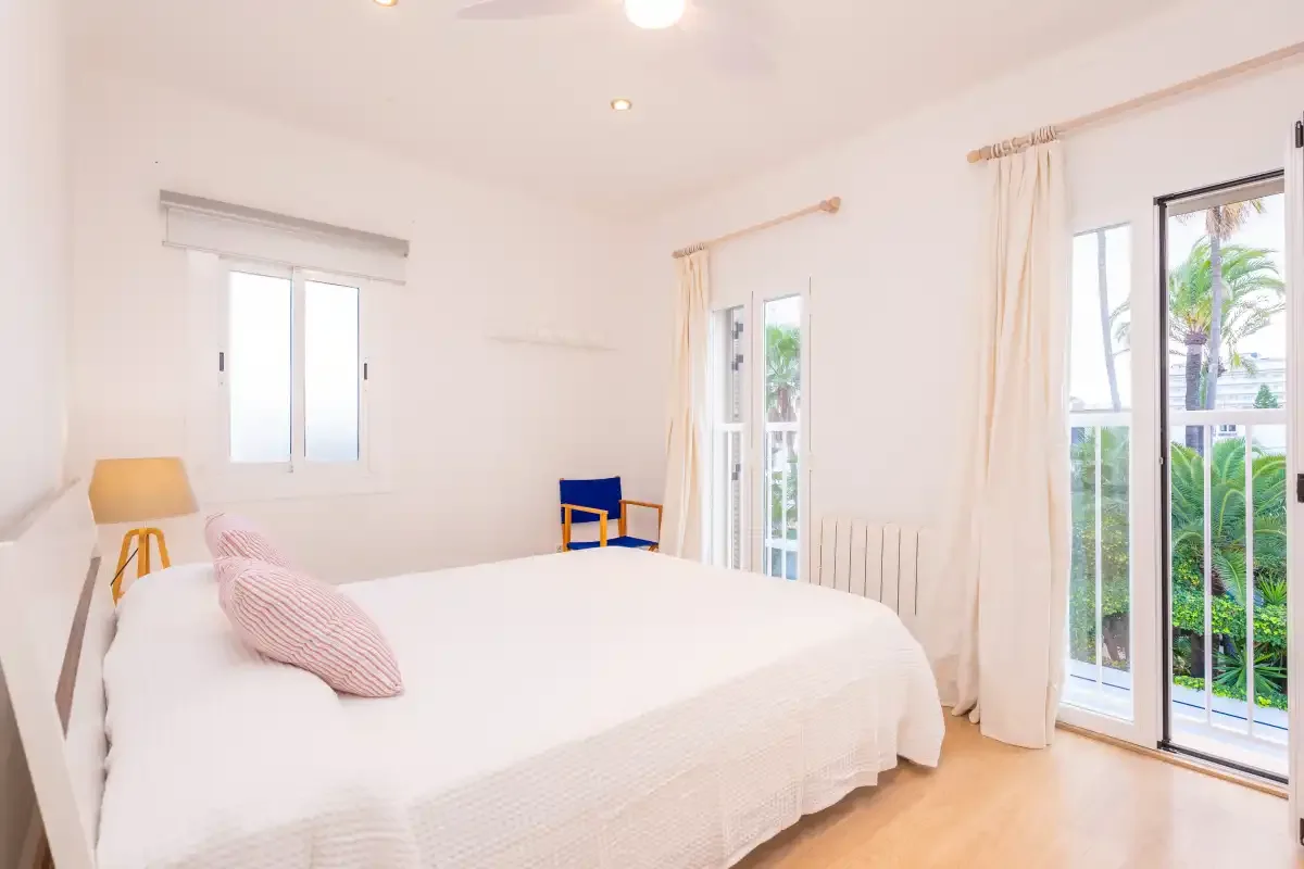 A bright bedroom with a bed and glass doors opening onto greenery.