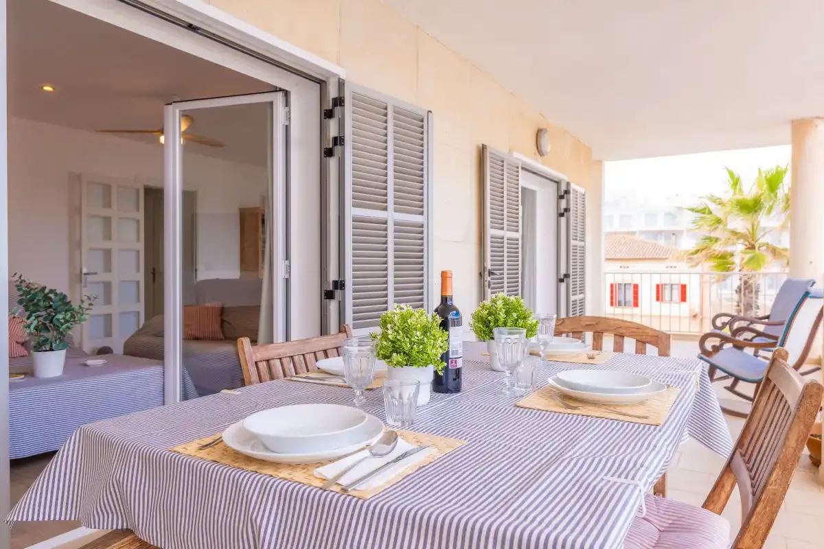 A covered patio dining area with a striped tablecloth and open doors.