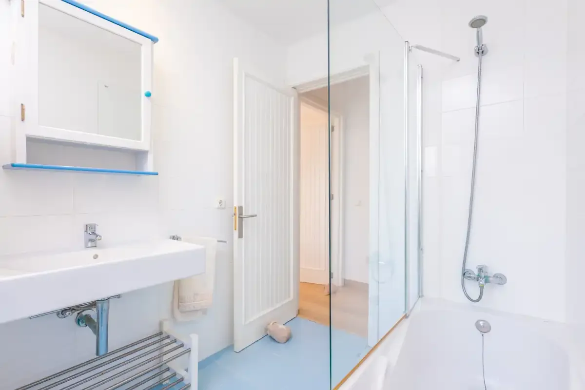 A bright bathroom with a sink, mirror, and shower.