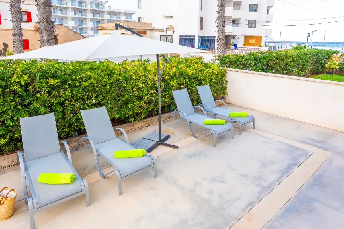An outdoor patio has reclining seating beneath a large shade umbrella.