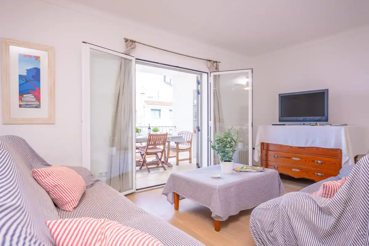 A living room with patterned seating, a coffee table, and an open balcony door.