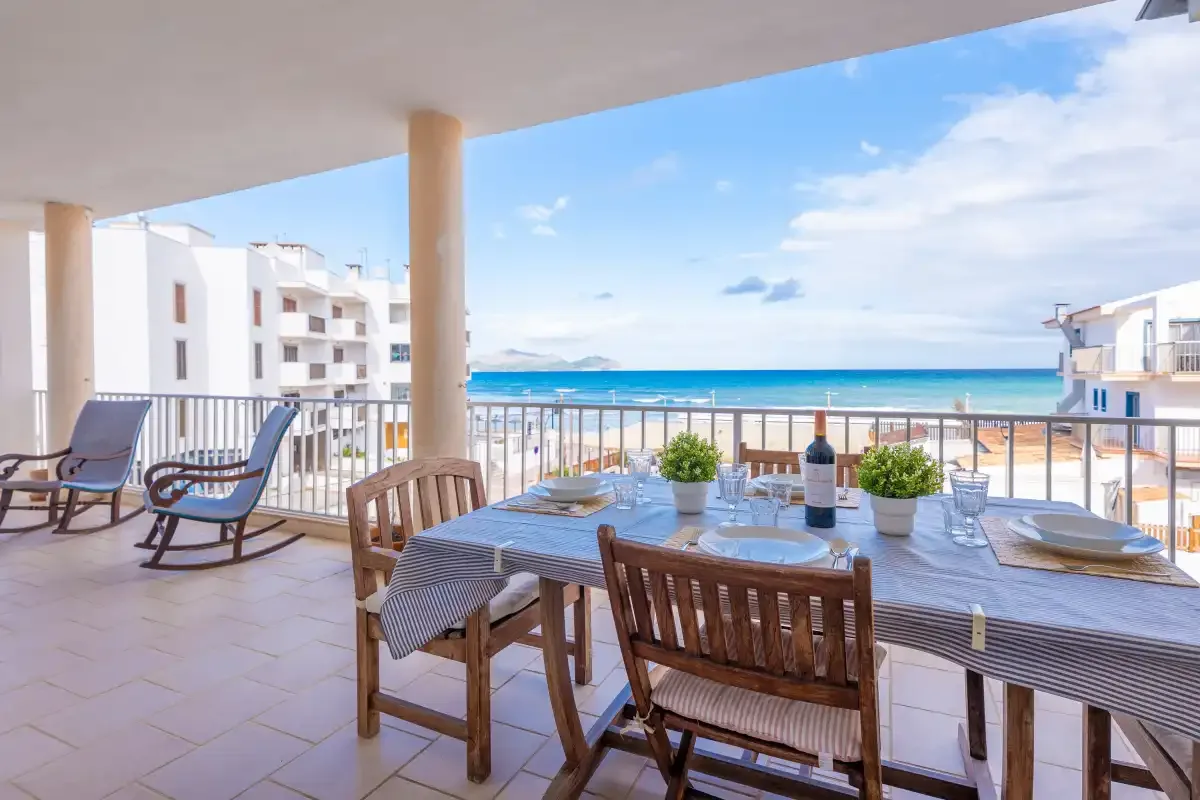 A covered balcony dining area overlooks the sea, with a table and outdoor seating.