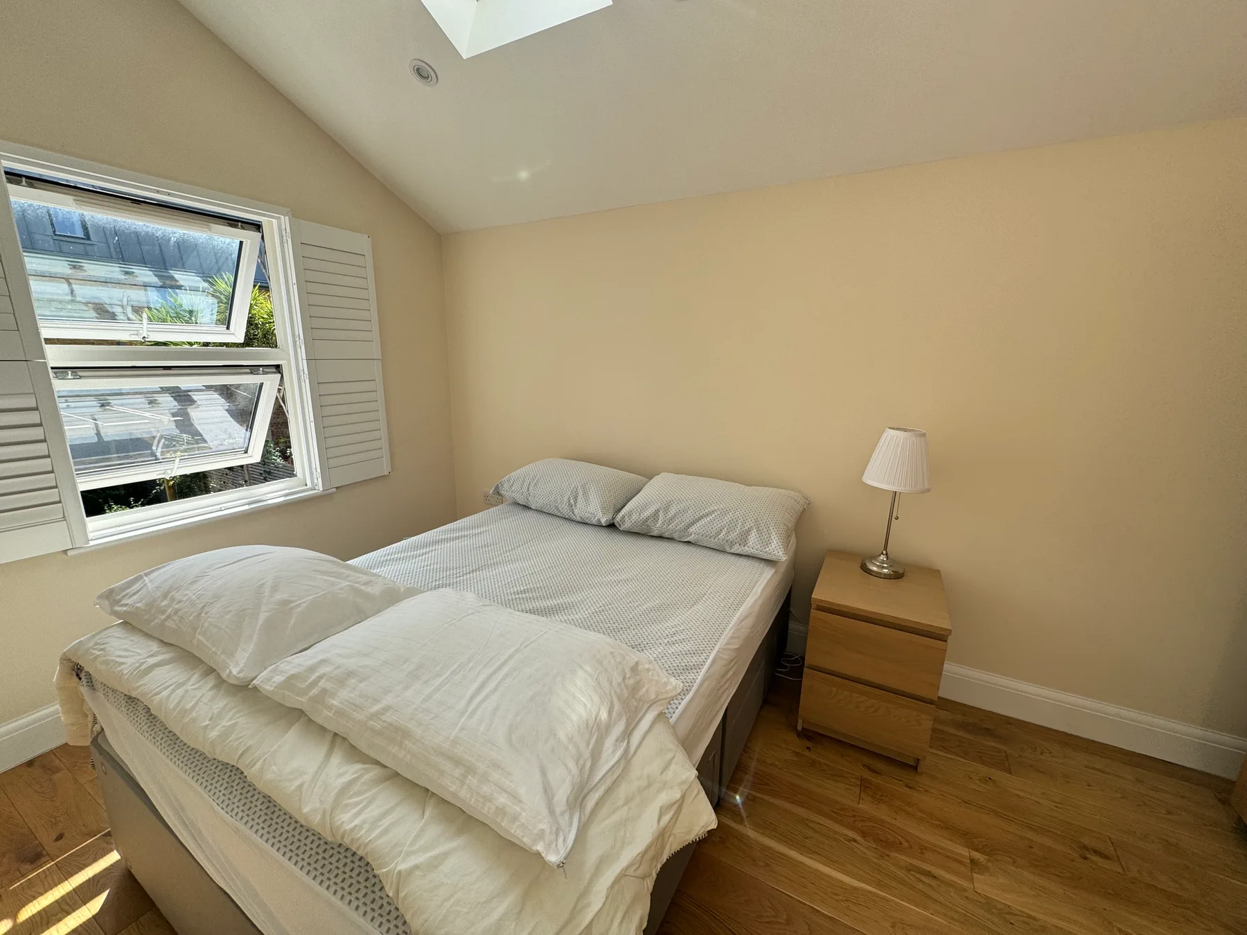 Un dormitorio con una cama, una mesita de noche y una ventana.