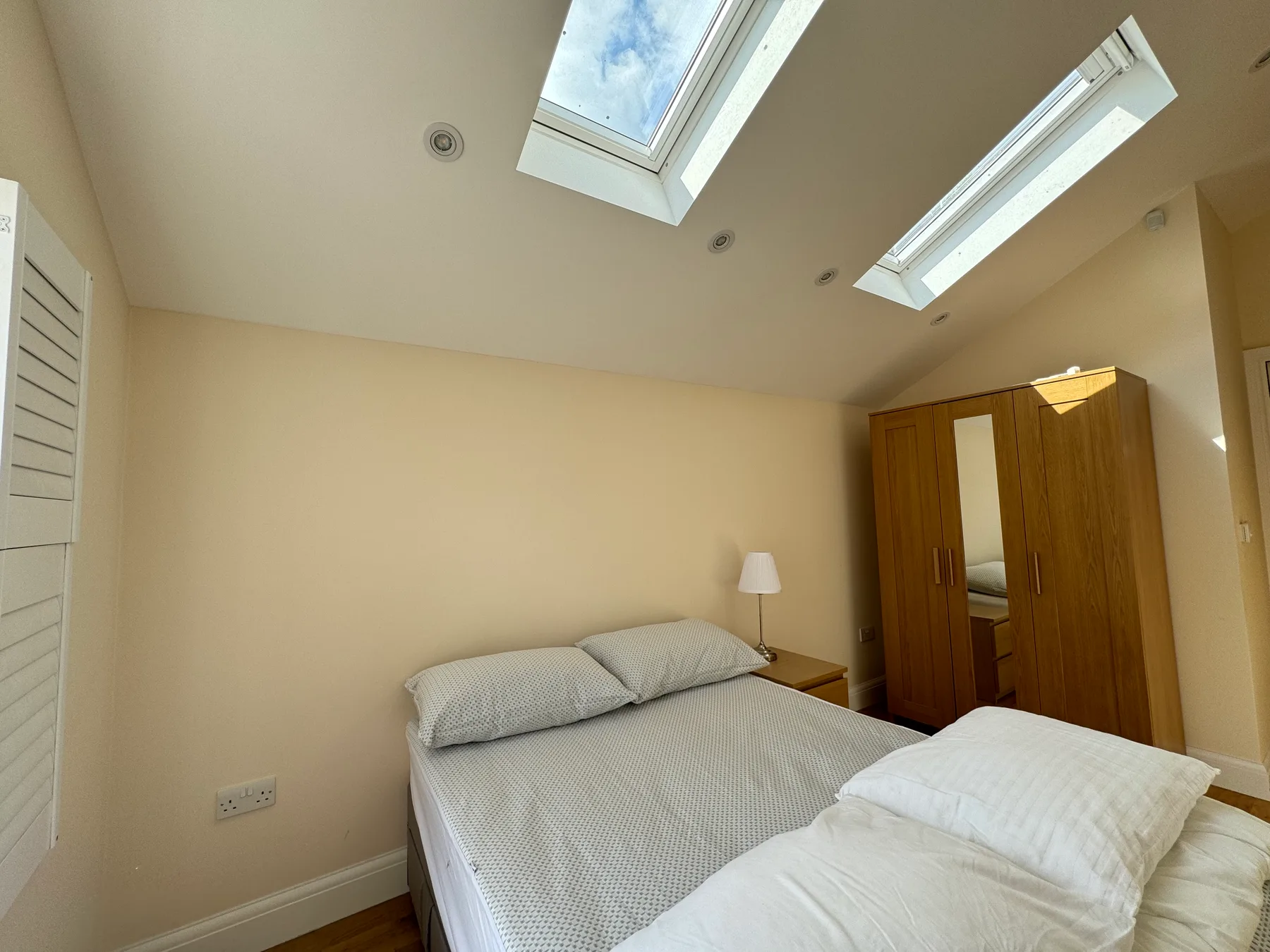 Dormitorio con una cama bajo dos tragaluces.