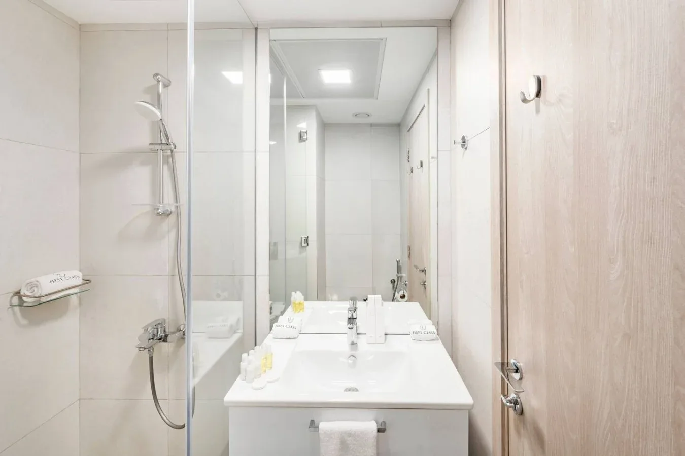 Un baño luminoso con una ducha junto a un lavabo y un tocador.