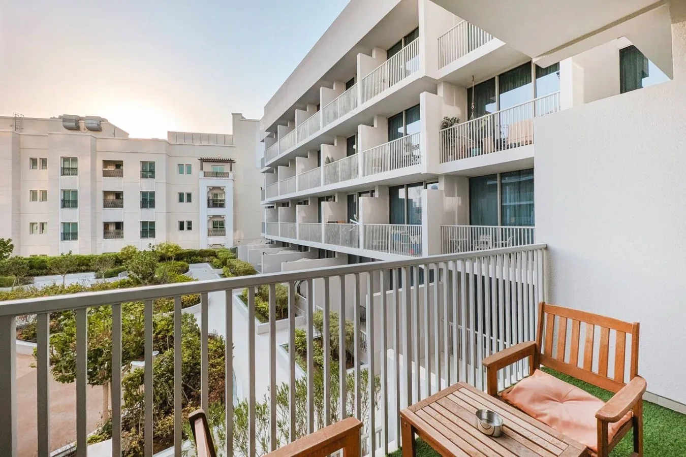 Un balcón da a un patio ajardinado y a edificios de apartamentos cercanos.