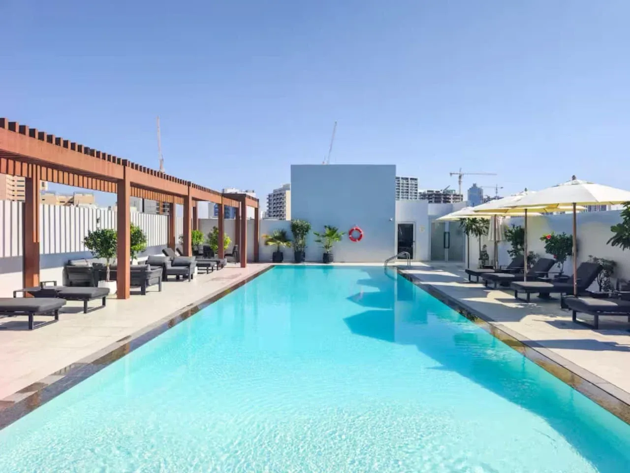 Una piscina en la azotea está rodeada de asientos y sombrillas.