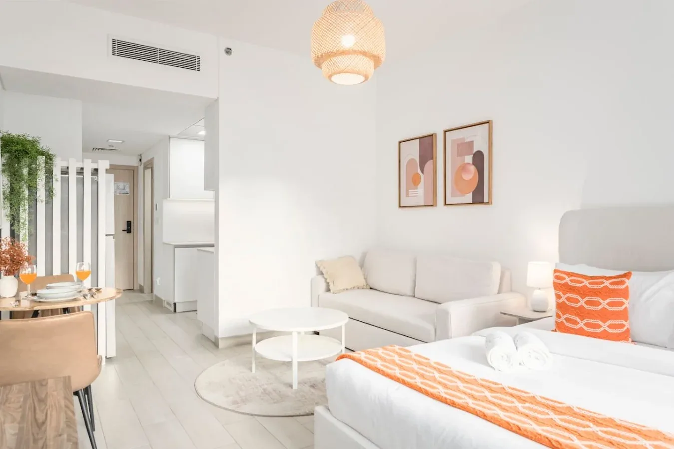 Un estudio luminoso con una zona de estar, una cama y un pequeño comedor.