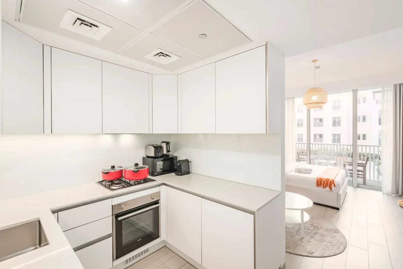 Un estudio luminoso combina una cocina compacta con una zona para dormir junto a la ventana.