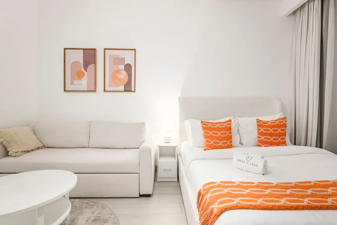 Un dormitorio tipo estudio luminoso con una cama y una zona de estar separada.