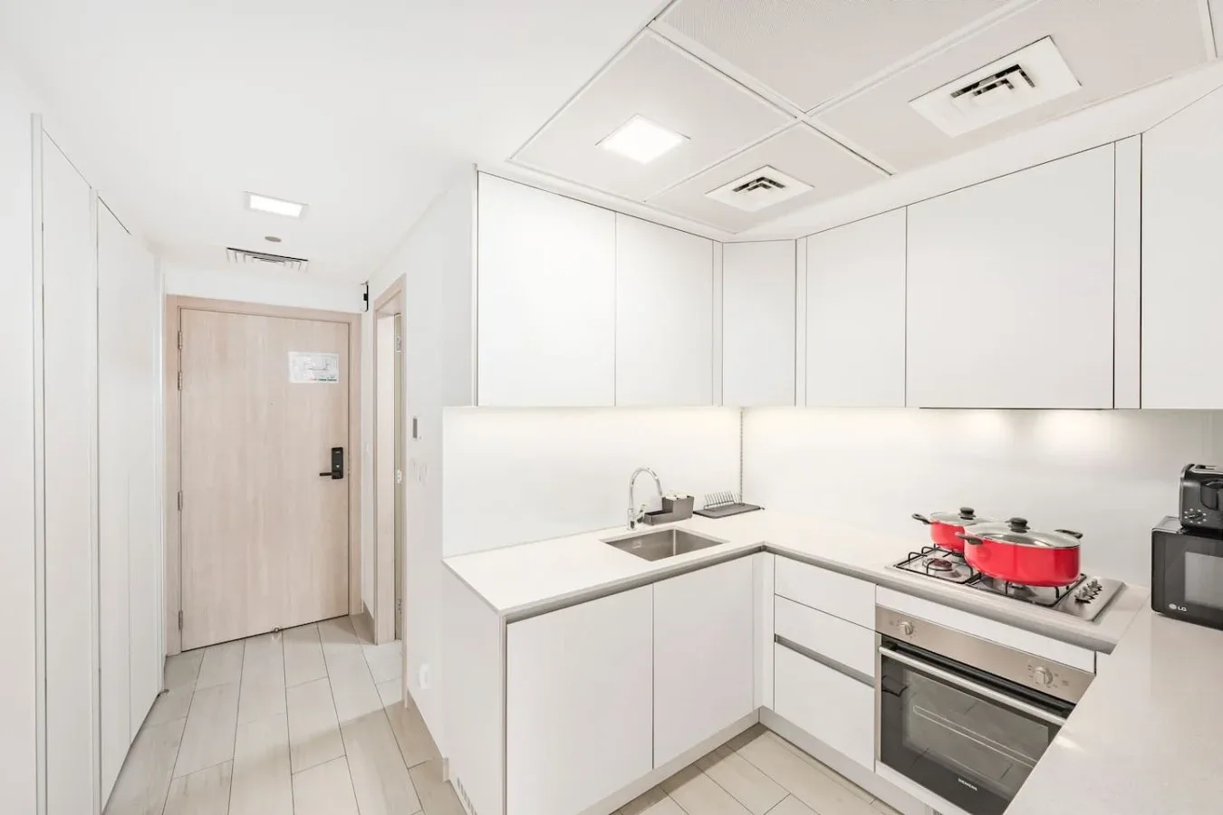 Una cocina luminosa con gabinetes blancos, una encimera y electrodomésticos.