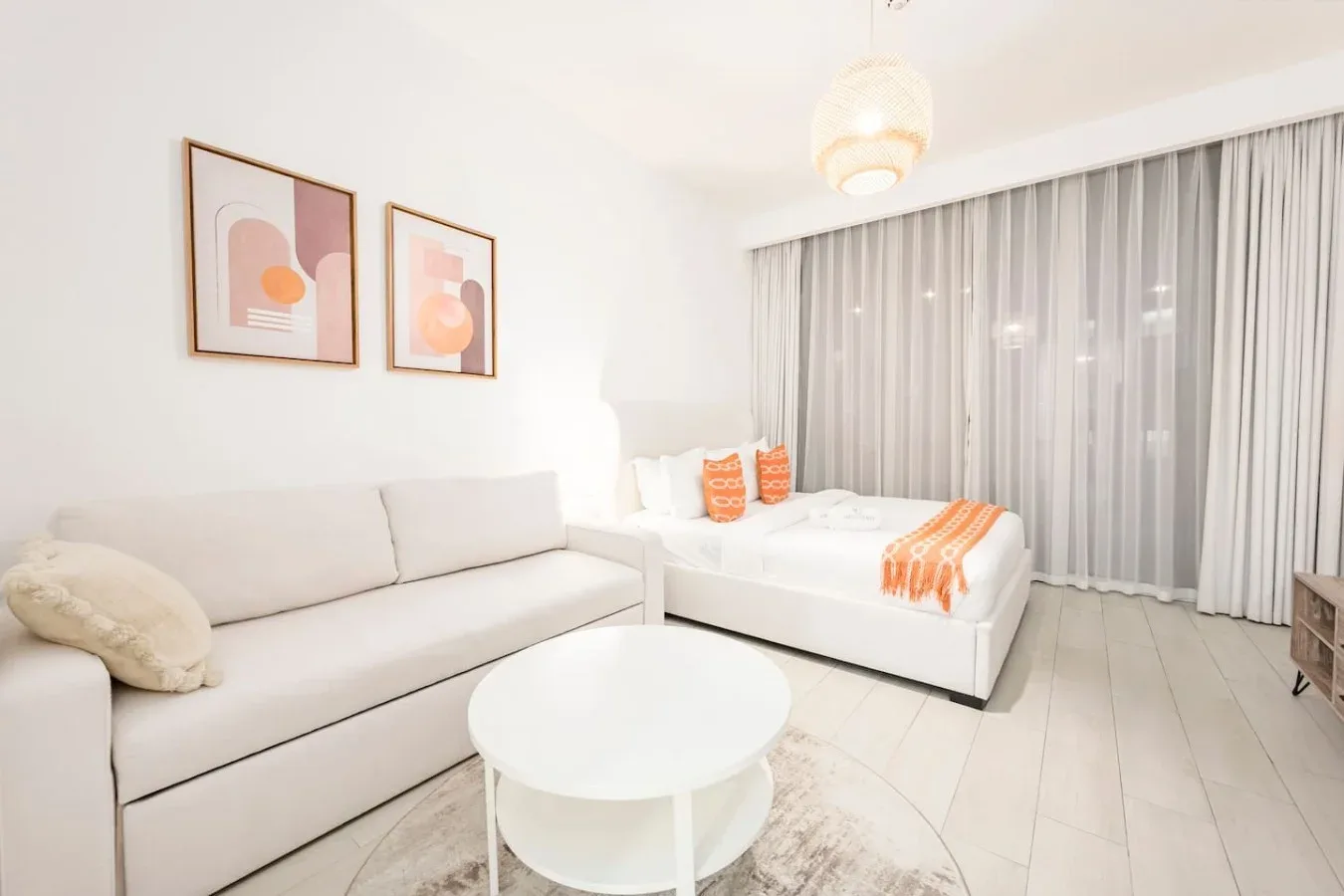 Una luminosa zona de estar de estudio con asientos, una cama y cortinas largas.