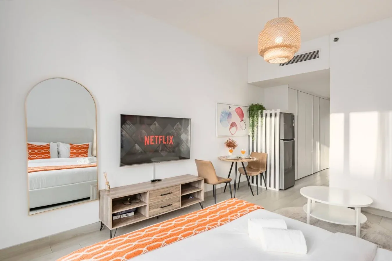 Una luminosa sala de estudio con televisor, mesa de comedor y cama.