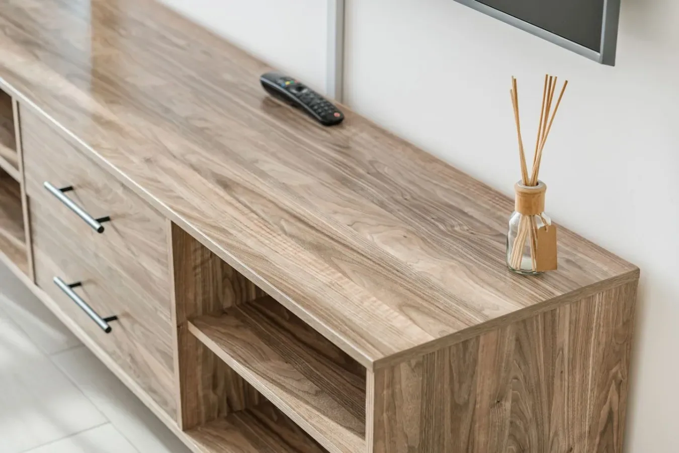 Un mueble de televisión de madera con estantes abiertos y un control remoto.