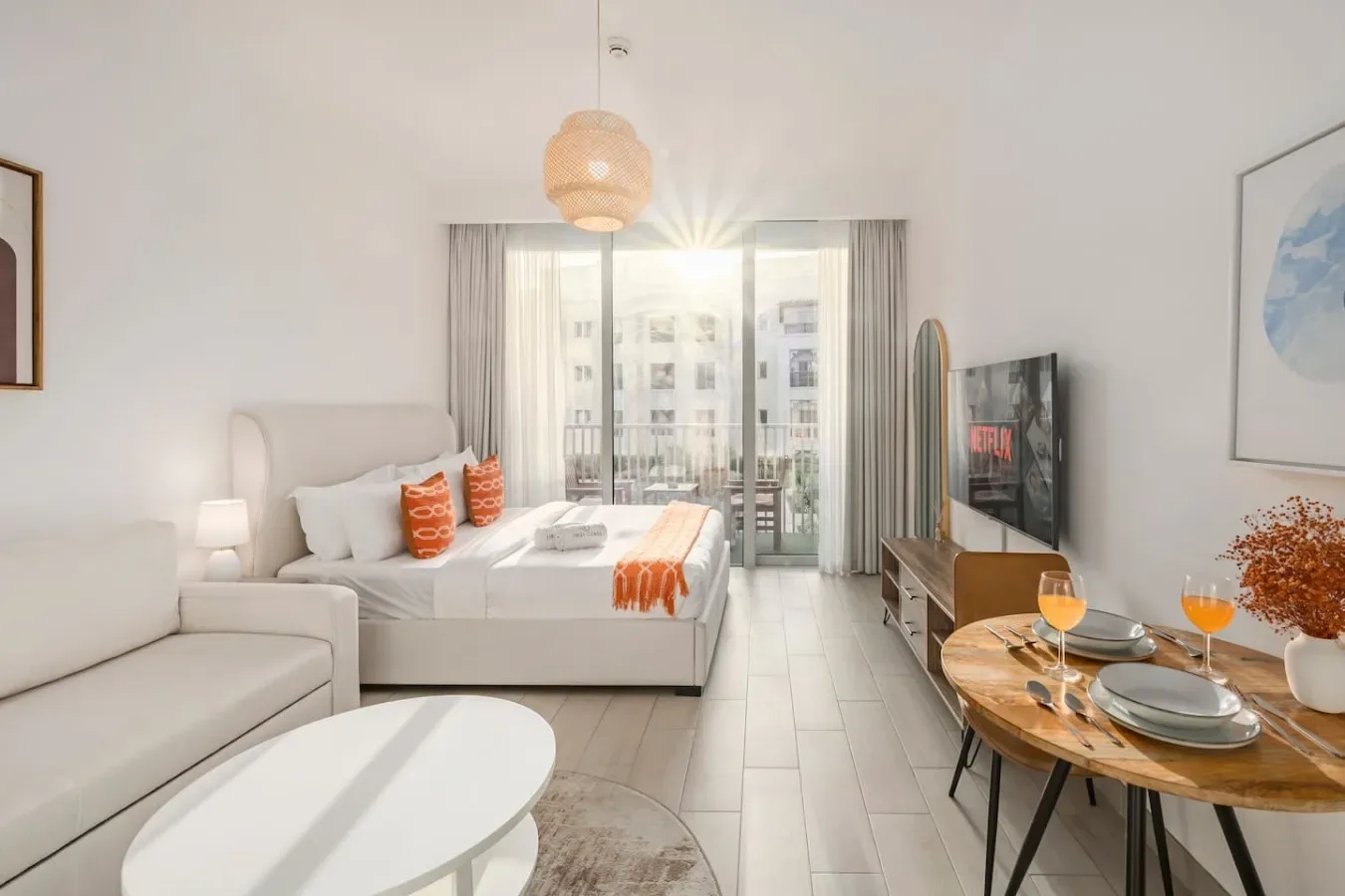 Un dormitorio luminoso con zona de estar, cama, asientos y una pequeña mesa de comedor.
