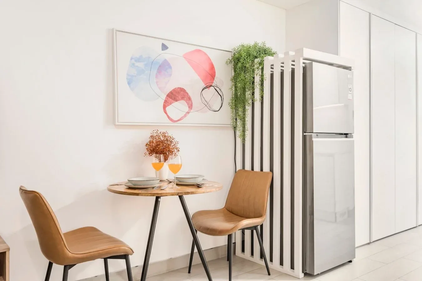 Un comedor con una mesa pequeña y asientos junto a un refrigerador.